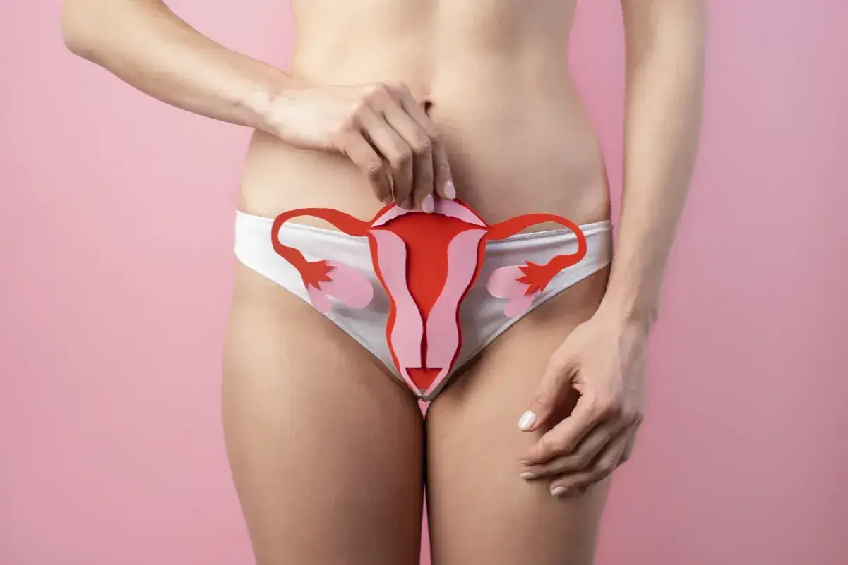 Kobieta trzyma wycięty z papieru model narządów rodnych, symbolizujący ból jajnika.