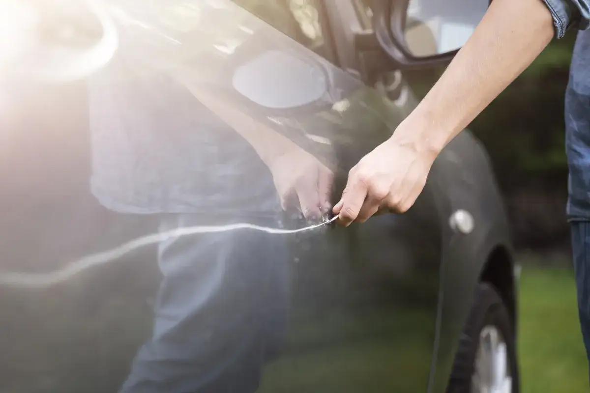 Hand poliert einen Kratzer am Auto. Informieren Sie sich über die auto kratzer entfernen kosten.