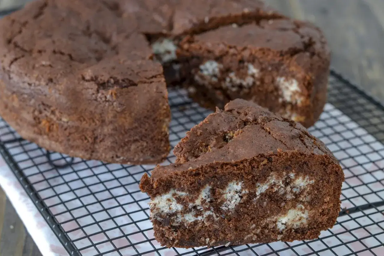 Torta cocco e cioccolato, con una fetta tagliata che rivela il ripieno bianco e soffice.