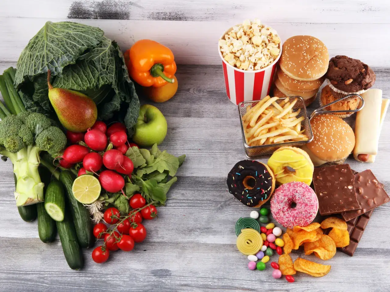 Warzywa i owoce po lewej, a po prawej słodycze i fast food. Wybór między zdrową dietą przy cholesterolu a pokusami.