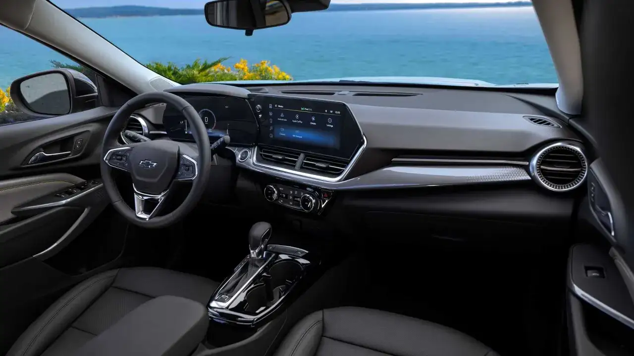 Wnętrze Chevrolet Trax z widokiem na morze. Nowoczesna deska rozdzielcza z ekranem dotykowym i cyfrowymi zegarami.
