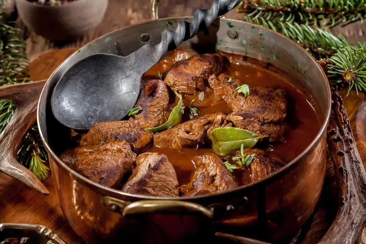Un saporito cinghiale alla cacciatora in un tegame di rame, pronto per essere servito.