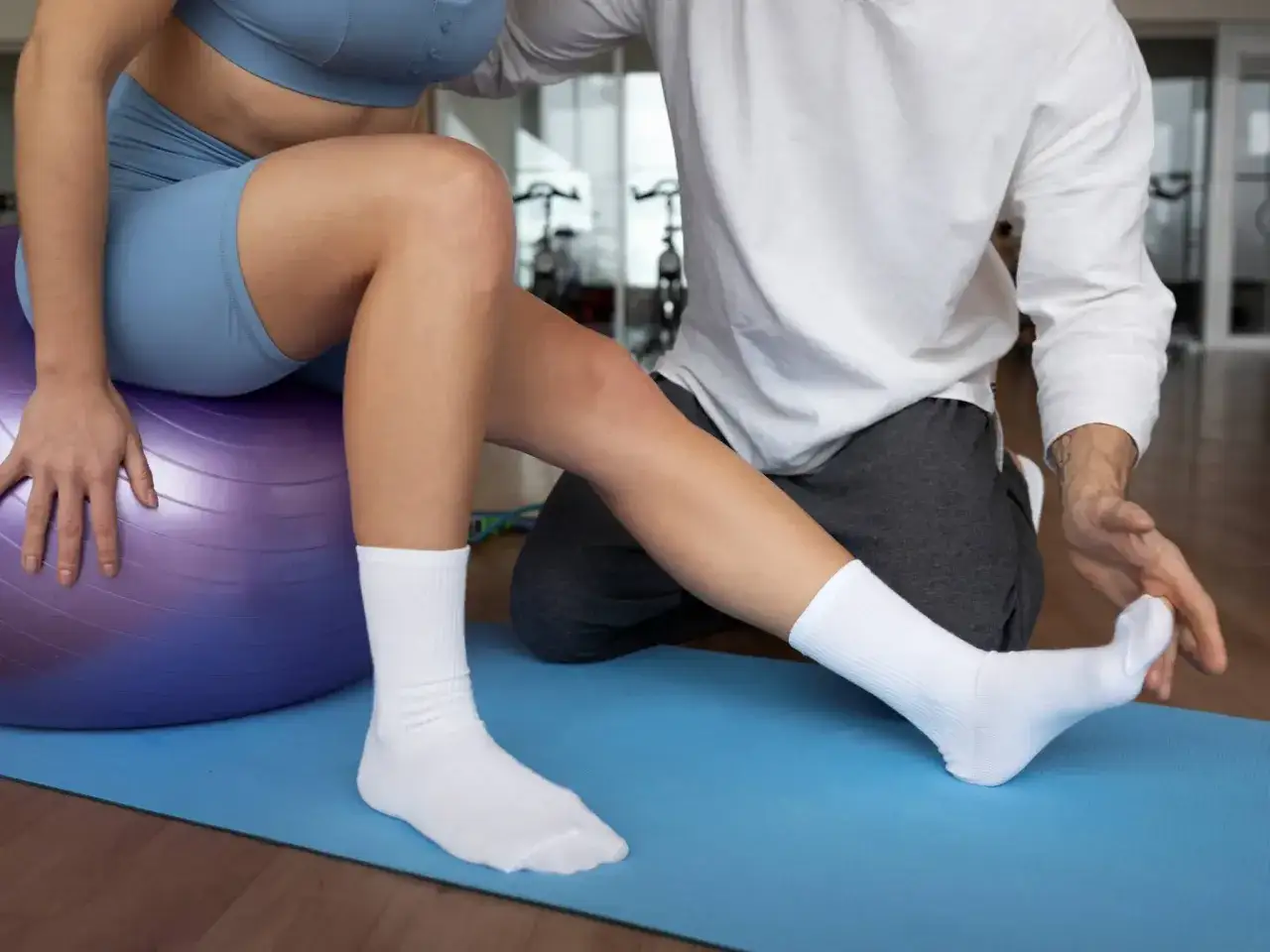 Therapeut hilft bei der Behandlung von Fersensporn mit Übungen auf einem Gymnastikball.