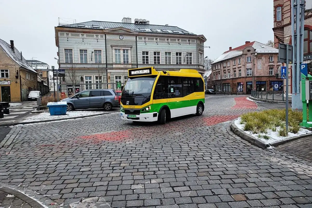 Żółto-zielony autobus miejski na brukowanej ulicy w Bydgoszczy. Na tablicy widnieje napis