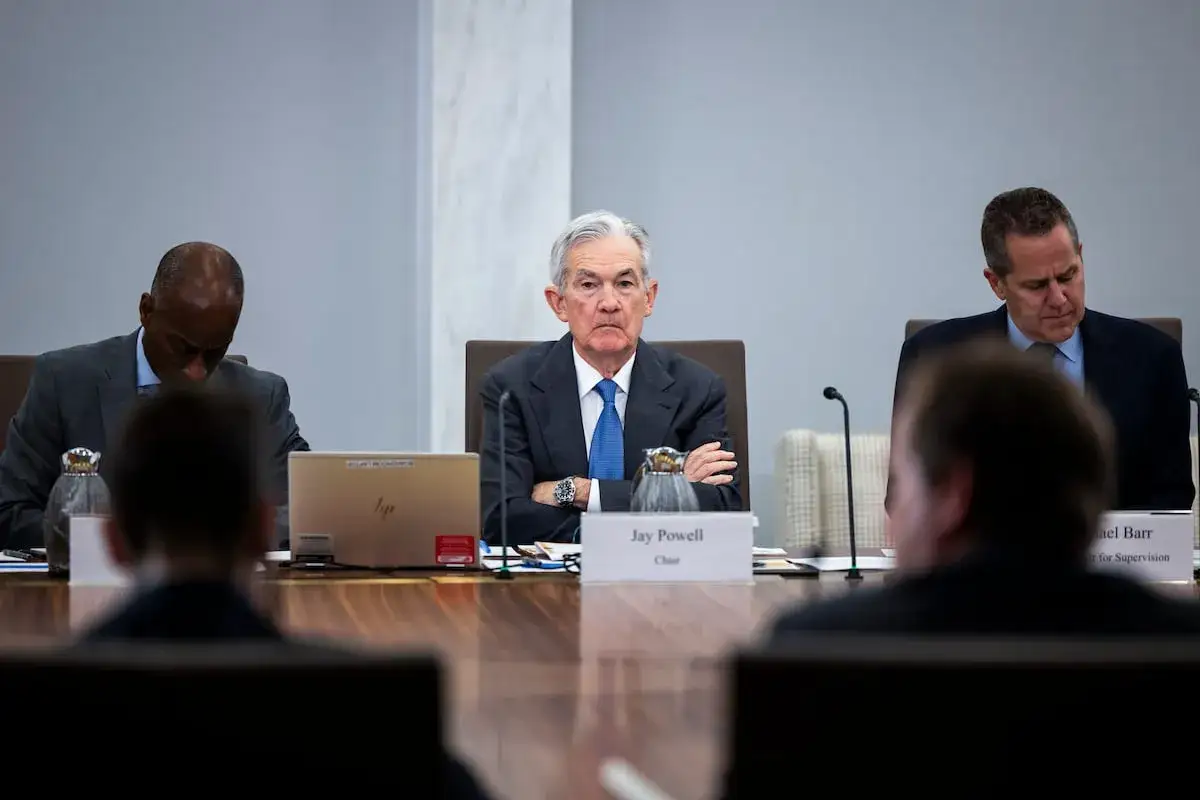 Jerome Powell, przewodniczący FOMC, siedzi z założonymi rękami, omawiając politykę monetarną.