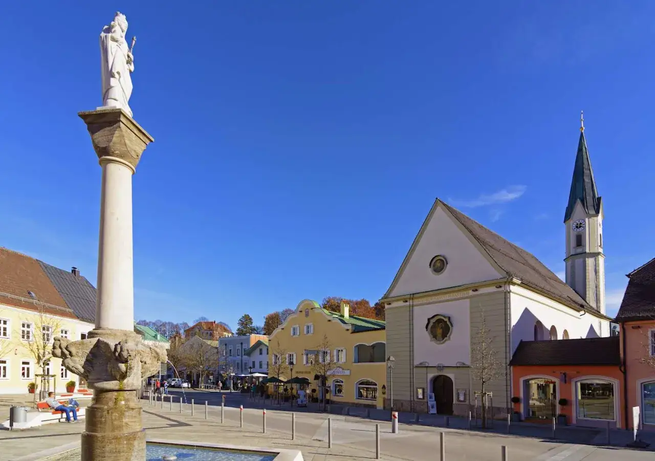 Säule mit Statue und die Stadtkirche Bad Aibling im sonnigen Ortskern.