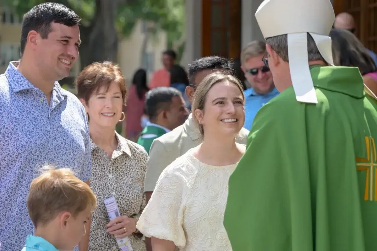 Glückliche Katholiken in den USA, eine Familie im Gespräch mit einem Bischof vor der Kirche.