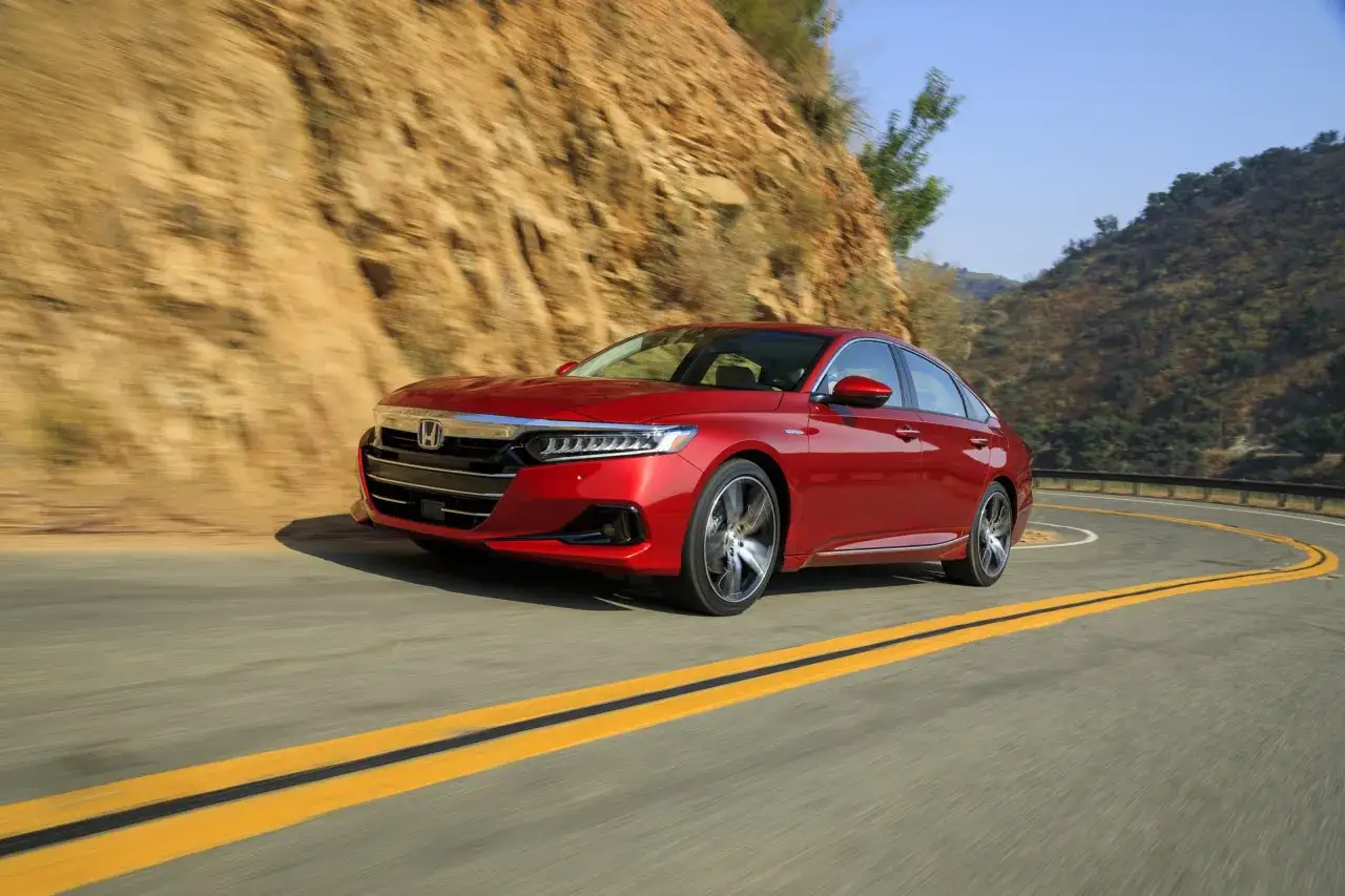 Czerwony Honda Accord pokonuje zakręt na górskiej drodze.