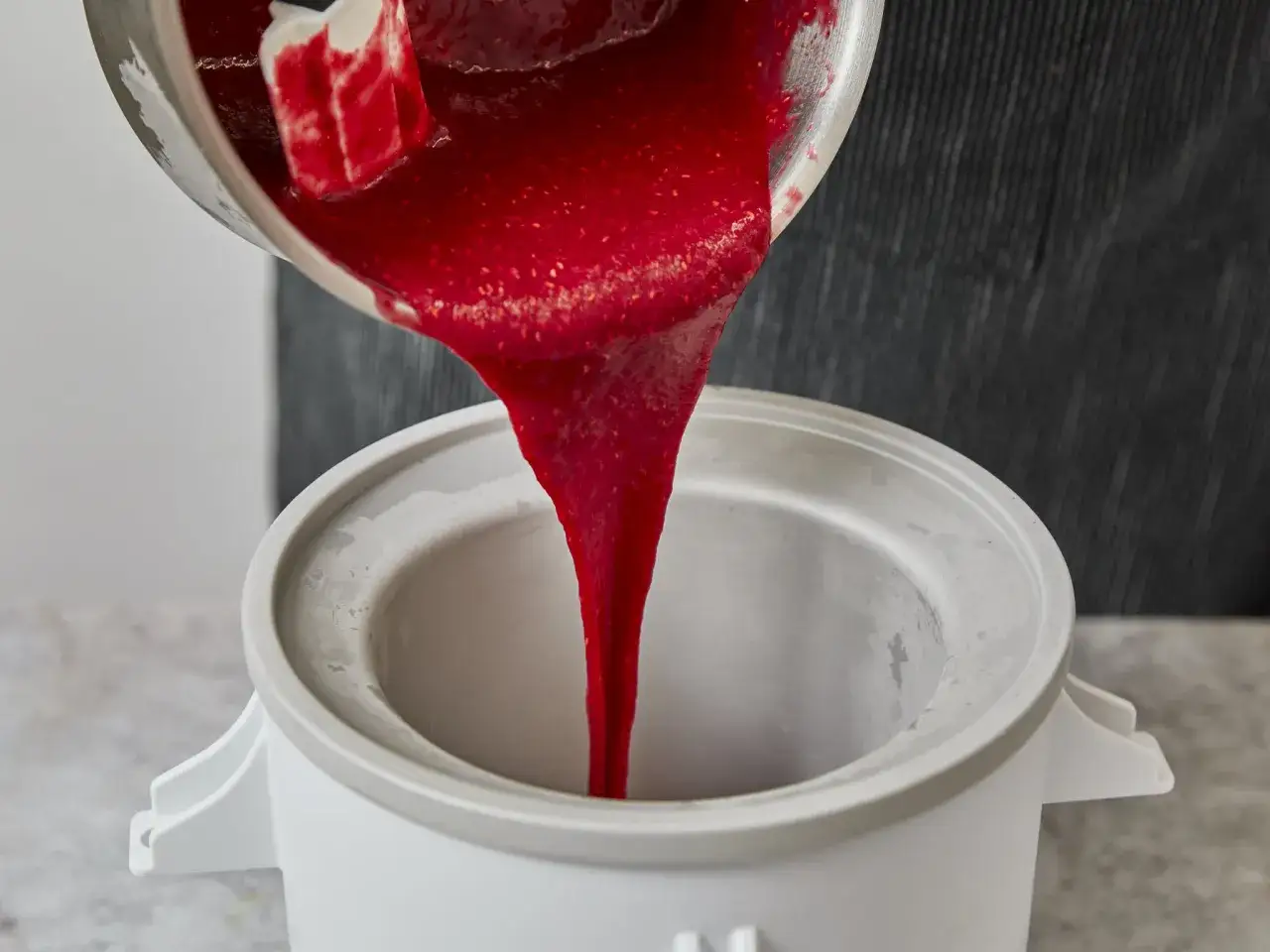 Leckeres Himbeersorbet wird in eine Eismaschine gegossen.