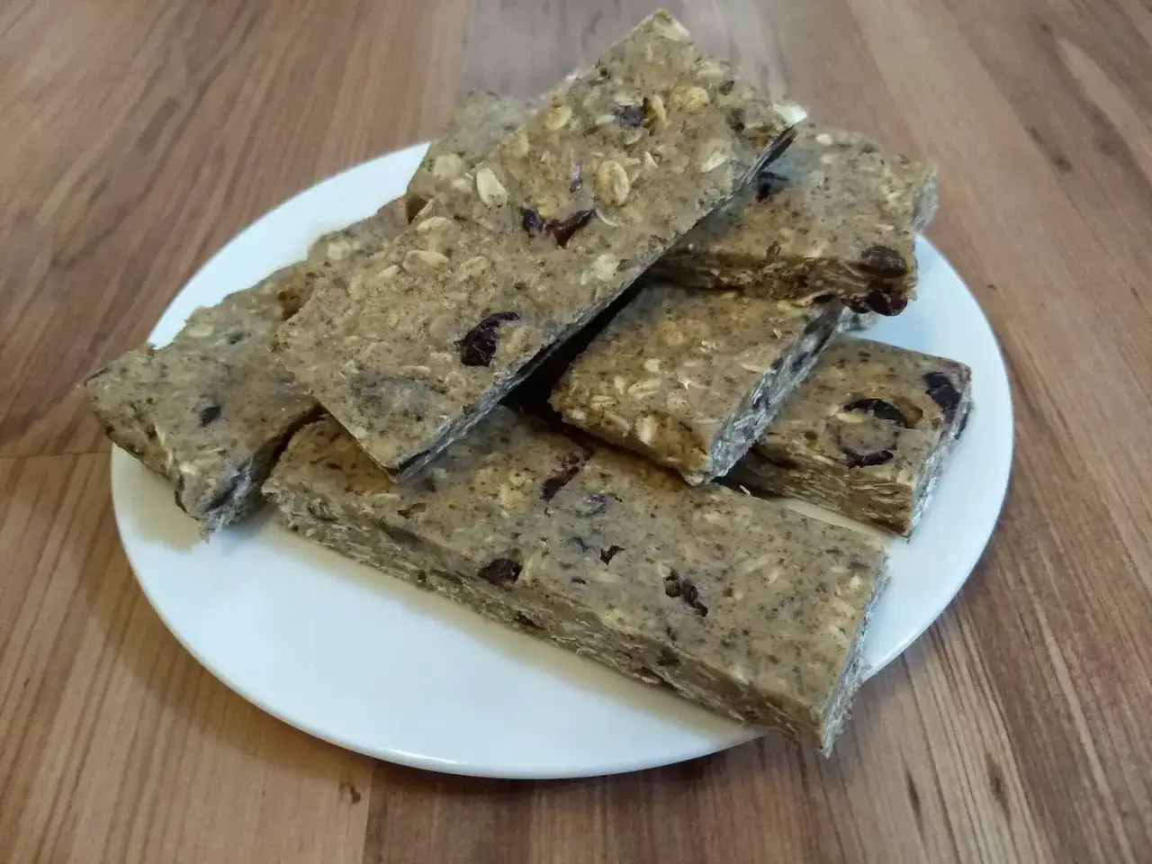 Domowe batony proteinowe z płatkami owsianymi i suszonymi owocami na talerzyku.
