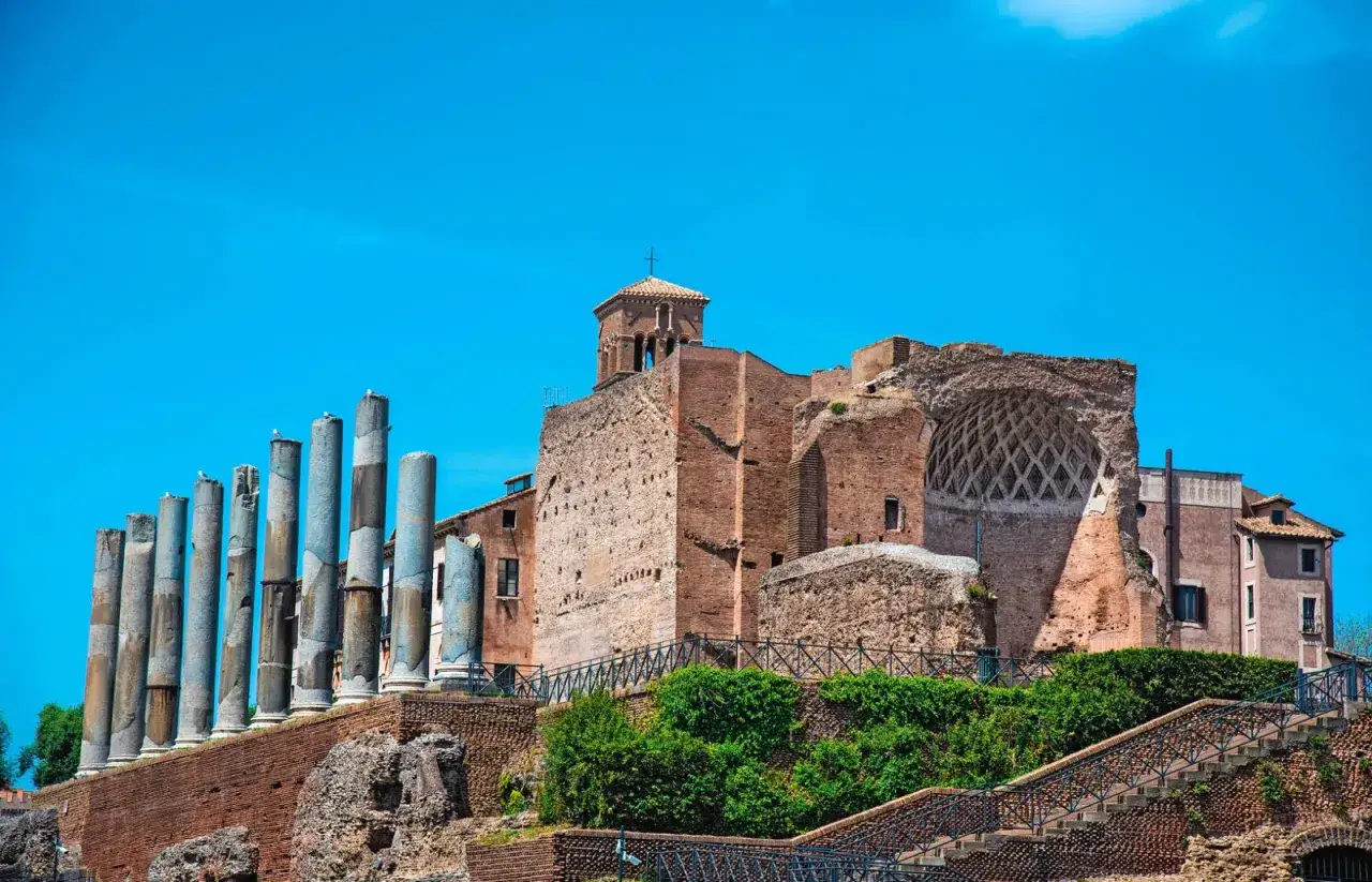 Resti antichi a Roma, dove si trova la Domus Aurea, con colonne imponenti e rovine di mattoni sotto un cielo azzurro.