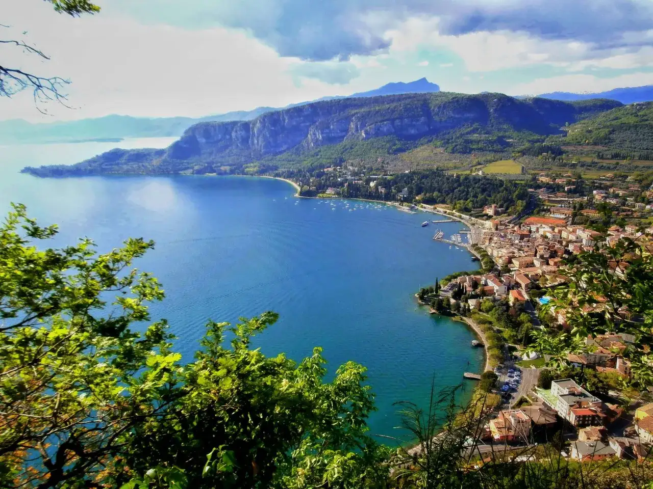 Vista panoramica del Lago di Garda, con montagne sullo sfondo e un borgo affacciato sull'acqua. Perfetto per scoprire cosa vedere!