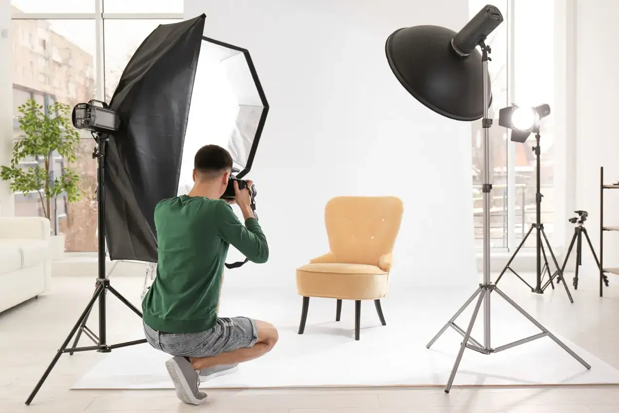 Mężczyzna na kursie fotografii wnętrz robi zdjęcie żółtego fotela w studiu z profesjonalnym oświetleniem.
