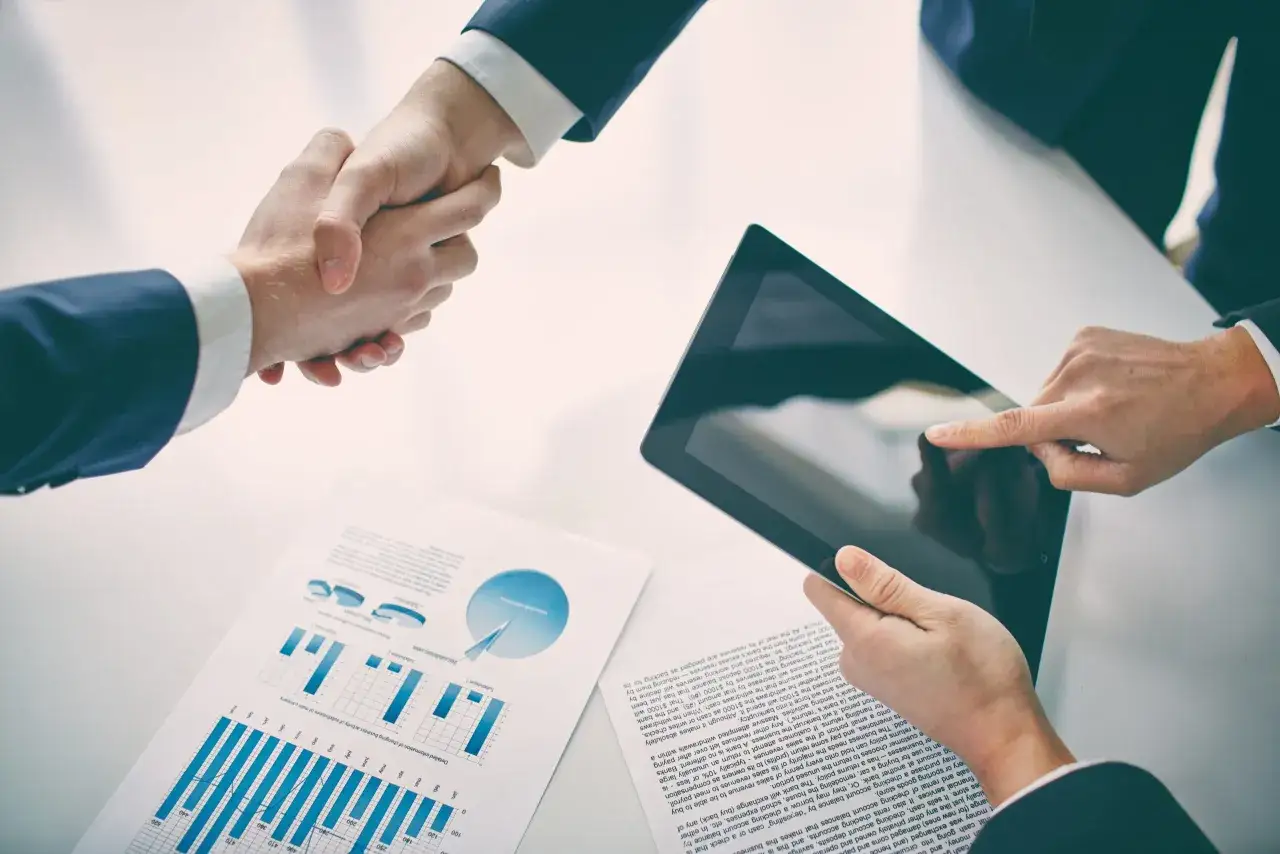 Apertón de manos y tableta con gráficos, indicando un acuerdo de firma cloud.