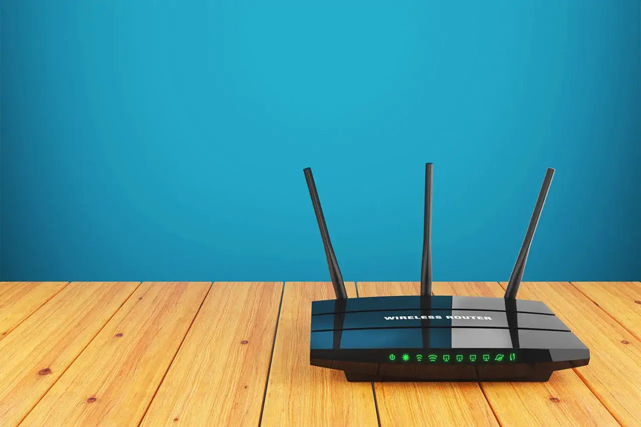 Router z antenkami na drewnianym blacie. Zadbaj o bezpieczeństwo w internecie, konfigurując swoje urządzenia.