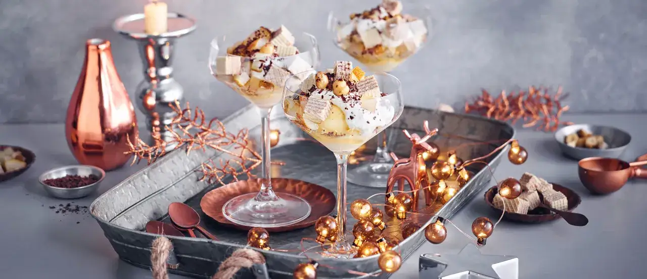 Festliches Eis-Dessert mit Waffeln und N&uuml;ssen, dekoriert mit Lichterkette und Rentierfigur &ndash; perfekt f&uuml;r Weihnachten.