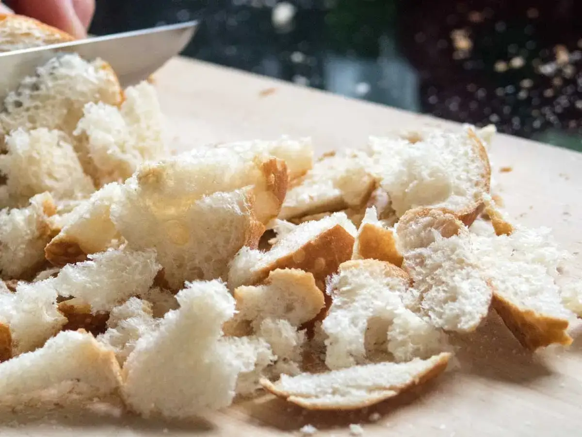 Frisches Brot wird für den Semmelschmarrn nach Omas Rezept in kleine Stücke geschnitten.