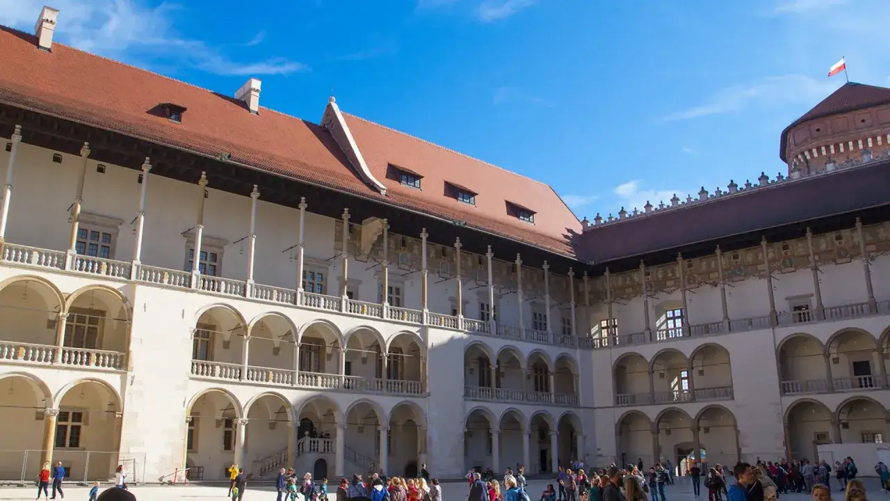 Dziedziniec Zamku Królewskiego na Wawelu, z arkadowymi krużgankami i turystami. Warto zobaczyć na Wawelu to miejsce pełne historii.