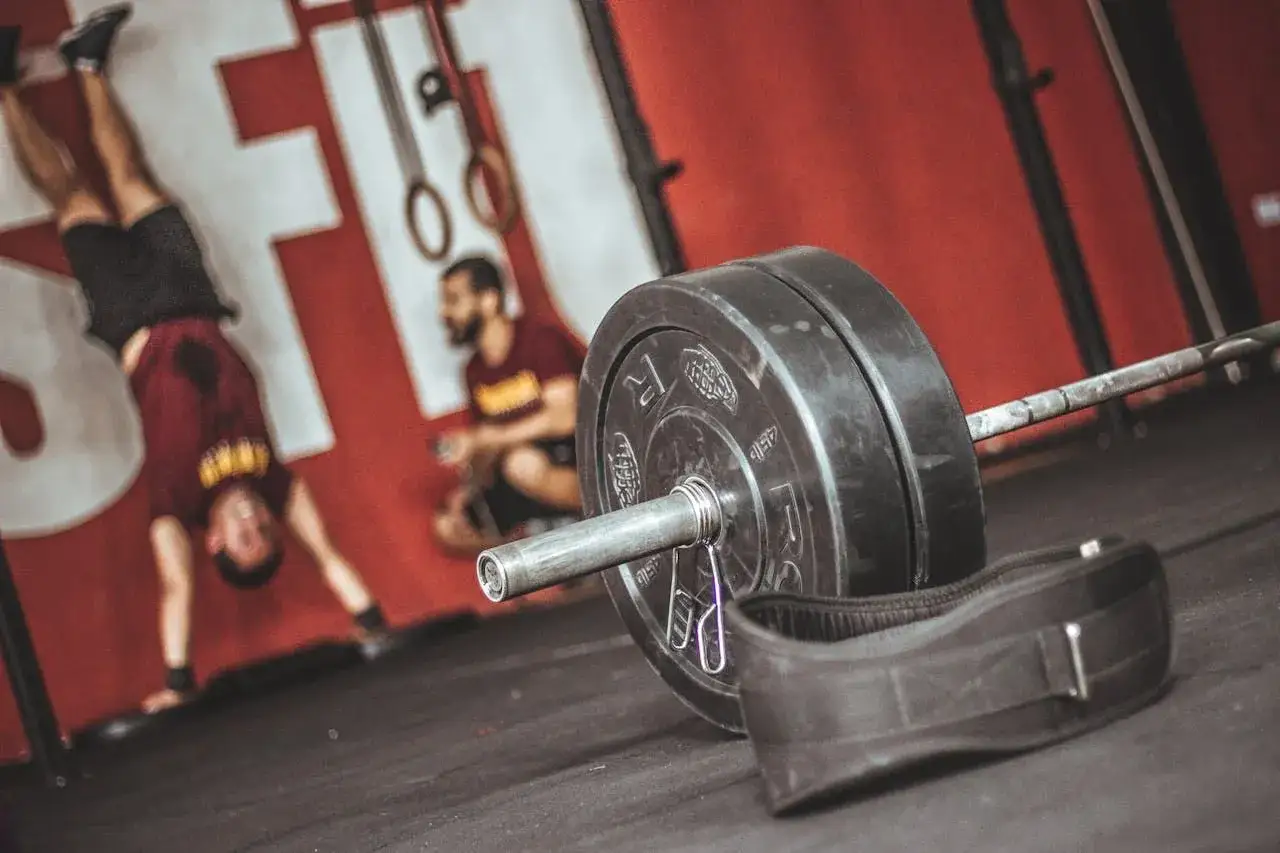 Ciężar, pas treningowy i zawodnik wykonujący stanie na rękach. Ile razy w tygodniu ćwiczyć crossfit?