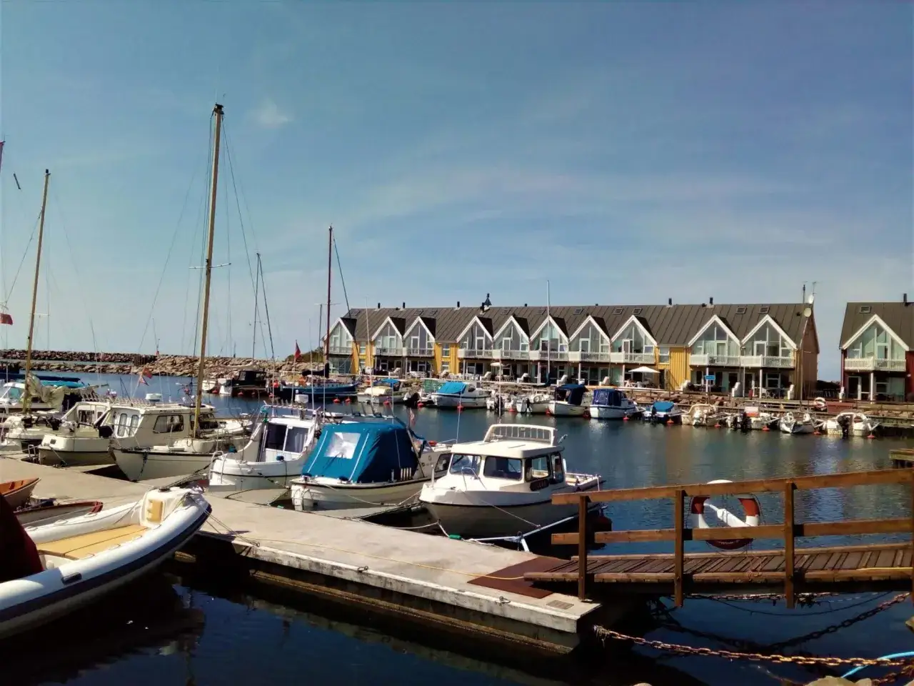 Port z łodziami i domkami w tle. Planujesz podróż rowerem na Bornholm? Koszty mogą być różne, ale widok jest wart każdej ceny.