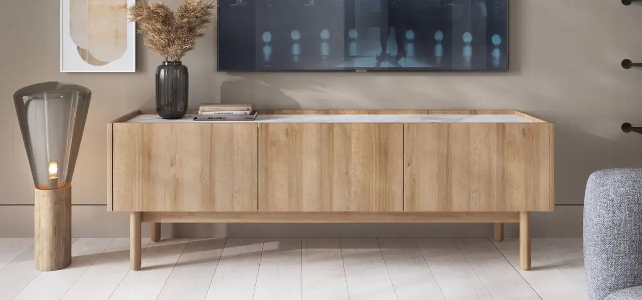 Drewniana szafka RTV z marmurowym blatem, wazon z trawą, książki i lampa. Idealne inspiracje, co postawić na szafce RTV.