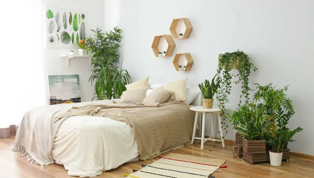 Ein gemütliches Schlafzimmer mit vielen grünen Pflanzen, die für frische Luft sorgen. Hexagonale Wandregale und ein Bild mit Blattmotiven schmücken die Wand.