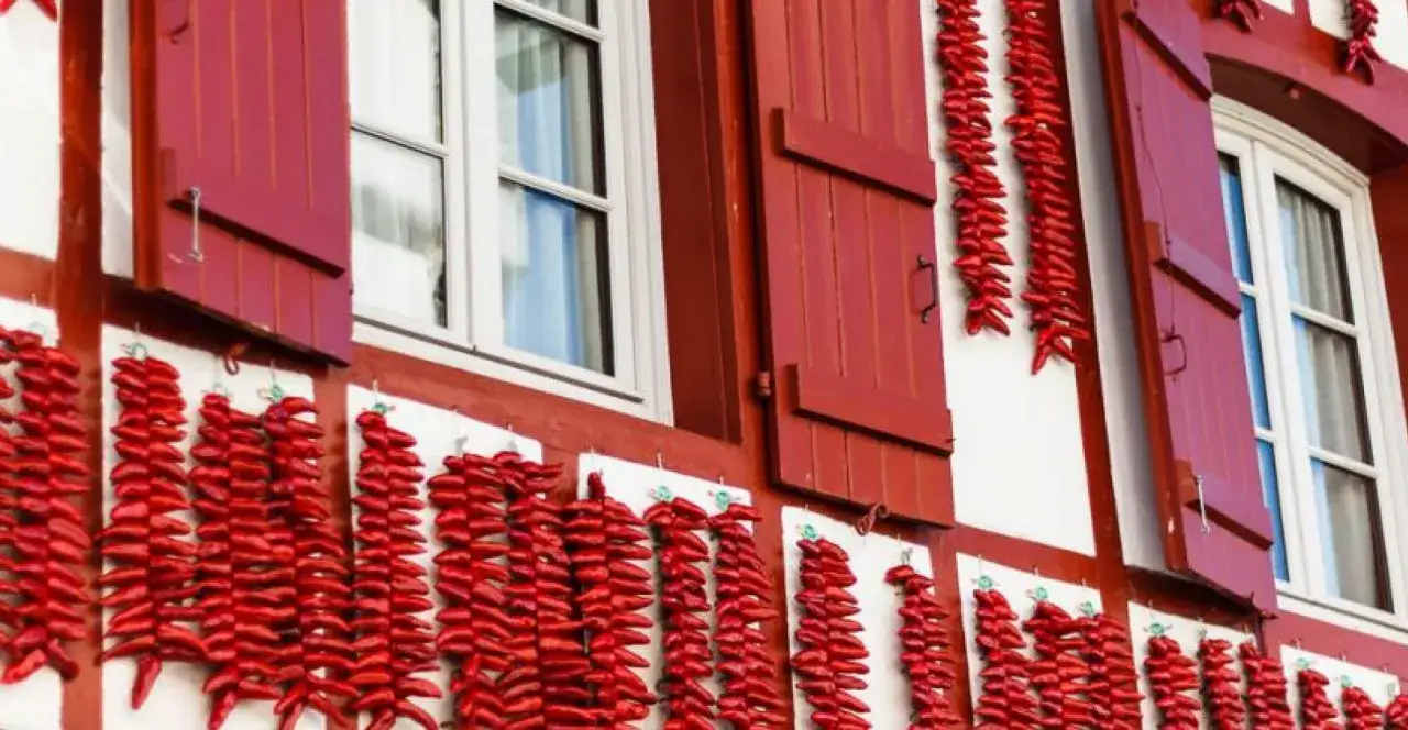Murs blancs et rouges typiques du Pays Basque, orn&eacute;s de guirlandes de piments s&eacute;ch&eacute;s. Id&eacute;al pour savoir combien de temps pour visiter Espelette.