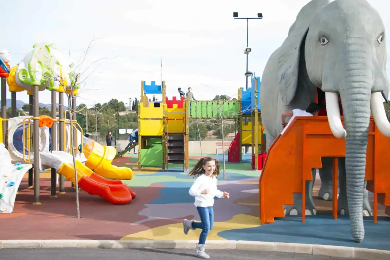 Un niño corre en un colorido parque infantil con un gran elefante de juguete. Un restaurante con parque infantil ideal para familias.