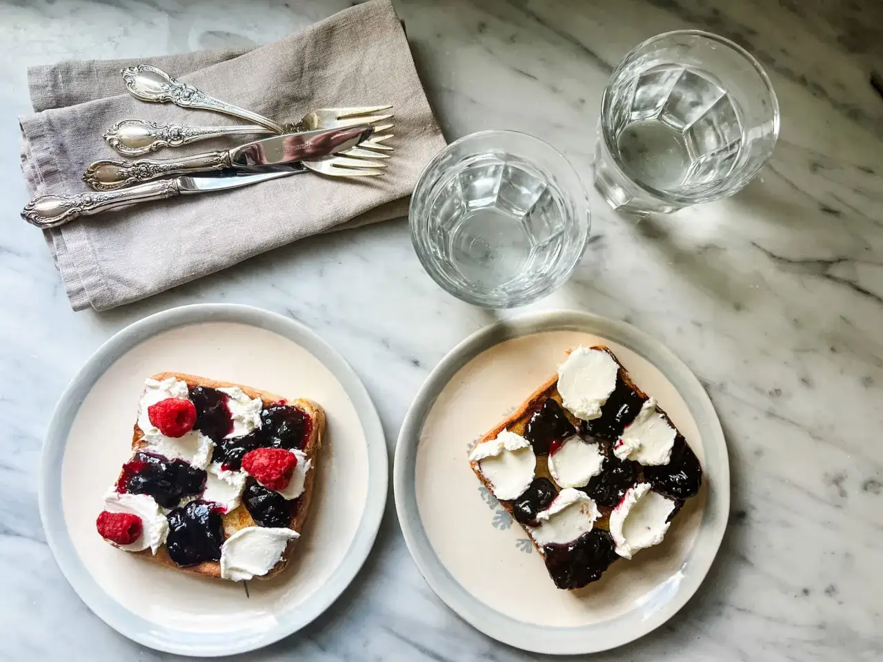 Zwei Toasts mit Brombeermarmelade, Frischkäse und Himbeeren. Perfekt, um Brombeermarmelade mit was zu mischen!