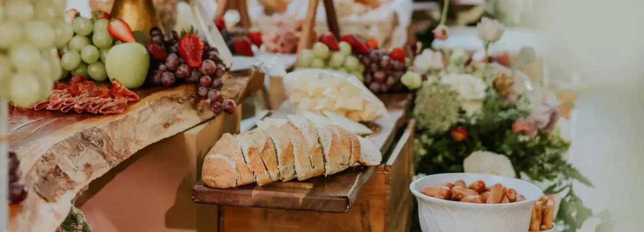 Un exemple de menu de mariage original : plateau de charcuterie, fromages, pain, fruits frais et petites saucisses, le tout joliment présenté.