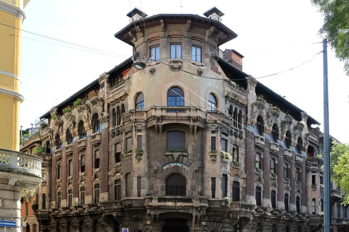Dettagli architettonici unici del **Palazzo Galimberti Milano**, con balconi ornati e sculture che emergono dalla facciata.