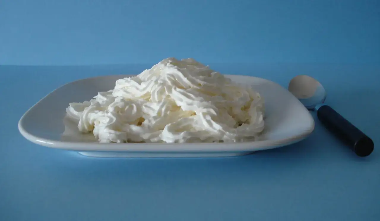 Montar nata es fácil con esta cremosa porción en un plato blanco, lista para decorar postres.