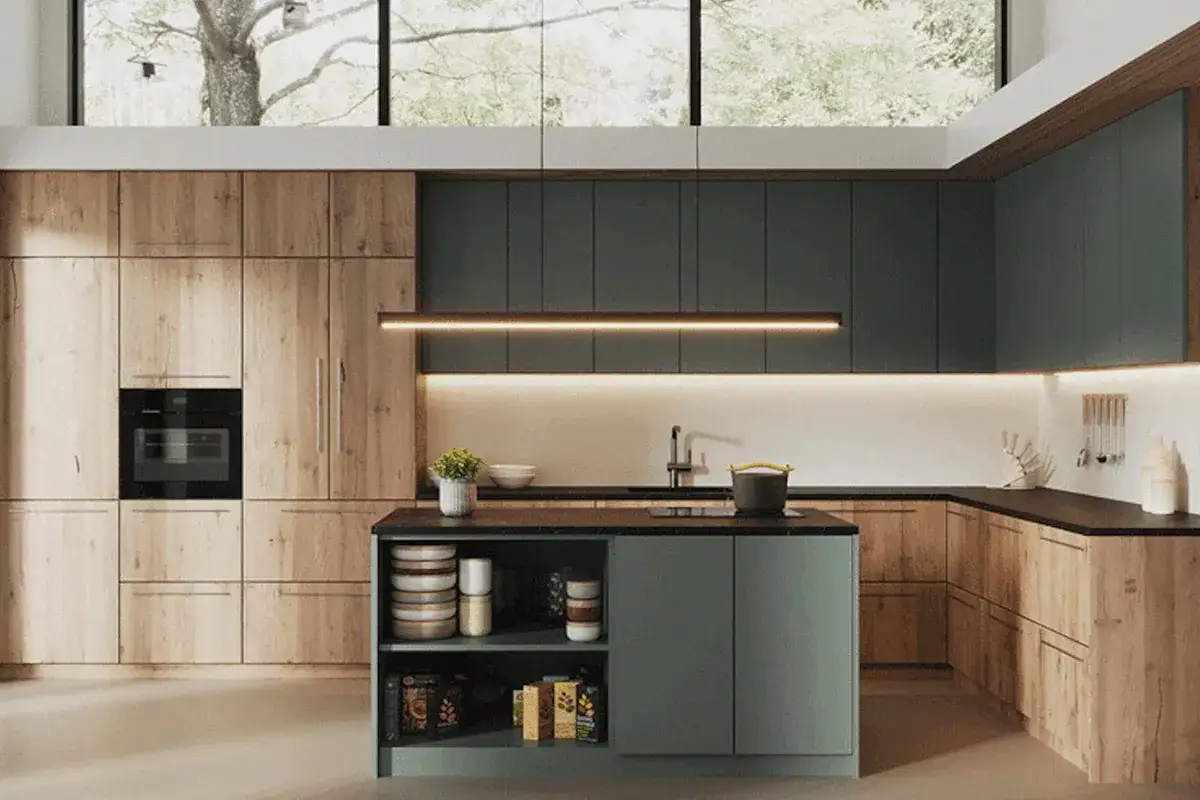 Cocina moderna con gabinetes de madera y verde azulado, isla central y gran ventana. Una reforma cocina soñada.