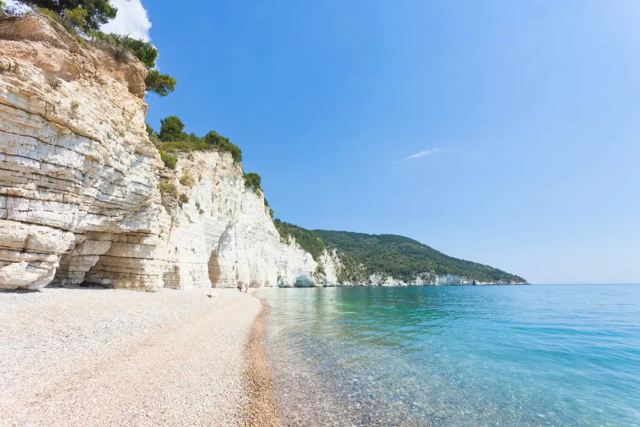 Spiaggia di ciottoli con scogliere bianche a picco sul mare cristallino. A Foggia c'&egrave; il mare, un paradiso naturale.