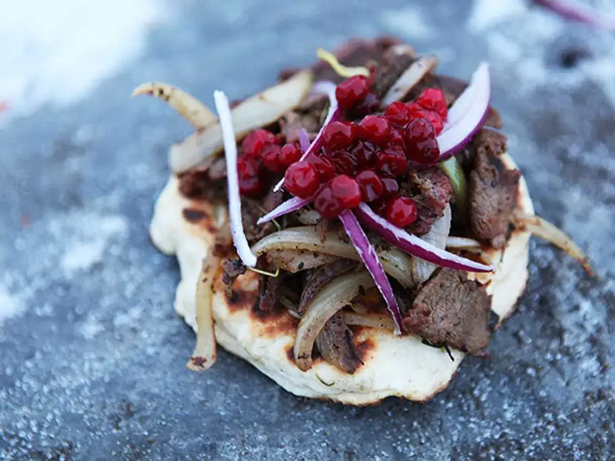 En smak av samisk mat: tunnbröd med renkött, stekt lök och lingon.