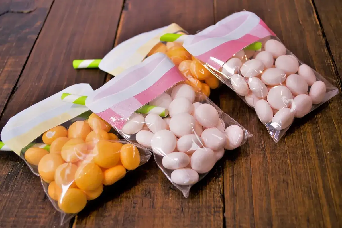 Tres bolsas transparentes con chuches caseras, unas naranjas y otras rosas, listas para regalar.