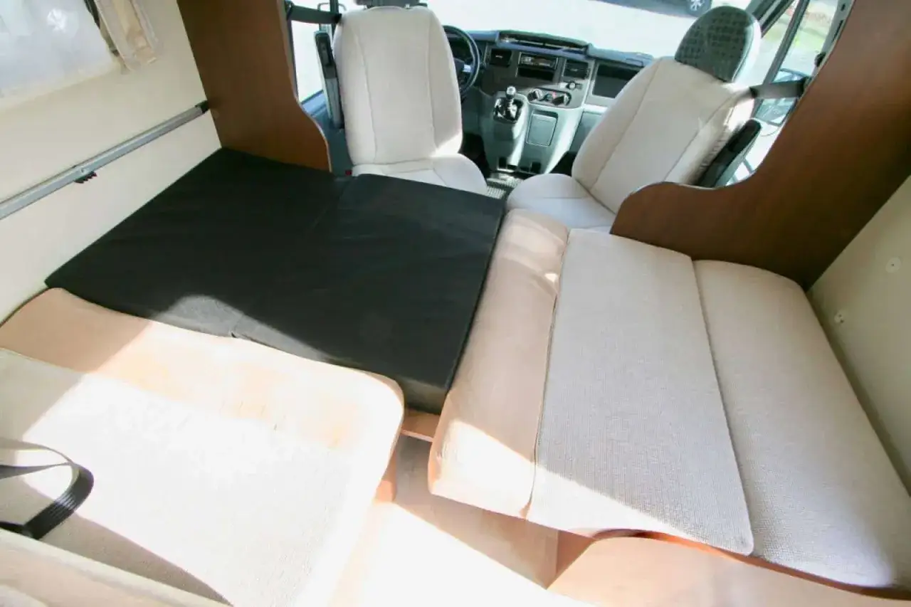 Montage lit dinette camping-car Fiat Ducato. Des coussins cr&eacute;ent un couchage confortable dans l'espace repas.