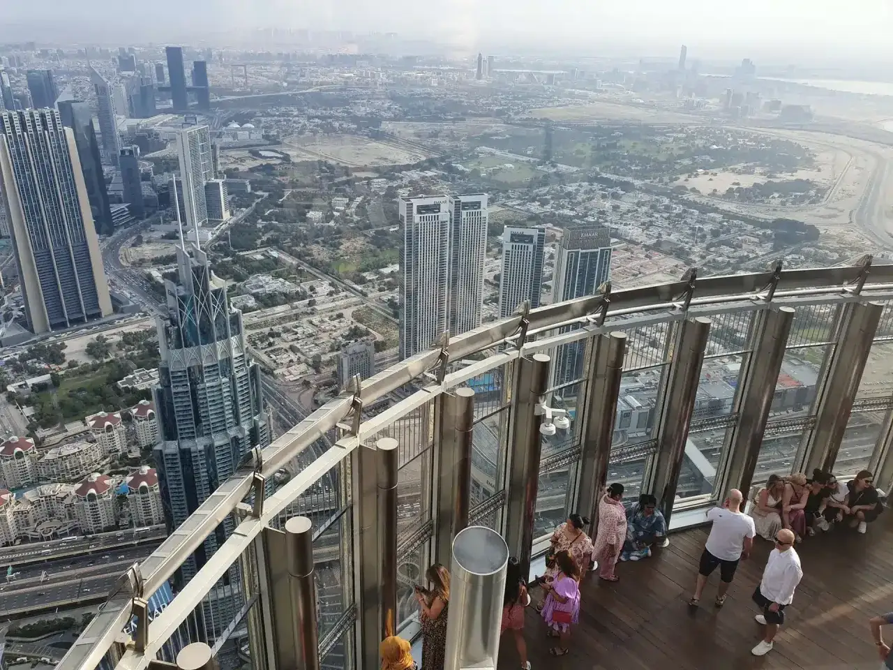 Widok z góry na Dubaj, gdzie jest Burj Khalifa. Ludzie podziwiają panoramę miasta z tarasu widokowego.