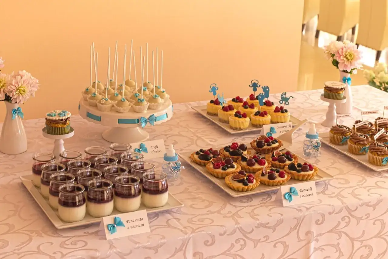 Słodki stół na chrzciny: ciasta na chrzciny, babeczki, tartaletki z owocami i panna cotta.