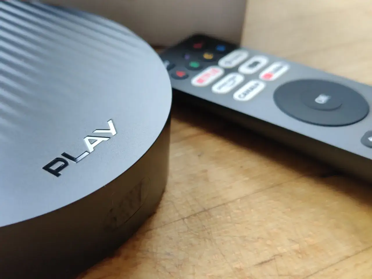 Czarny dekoder Play z pilotem, na którym widać przyciski Netflix i Canal+.