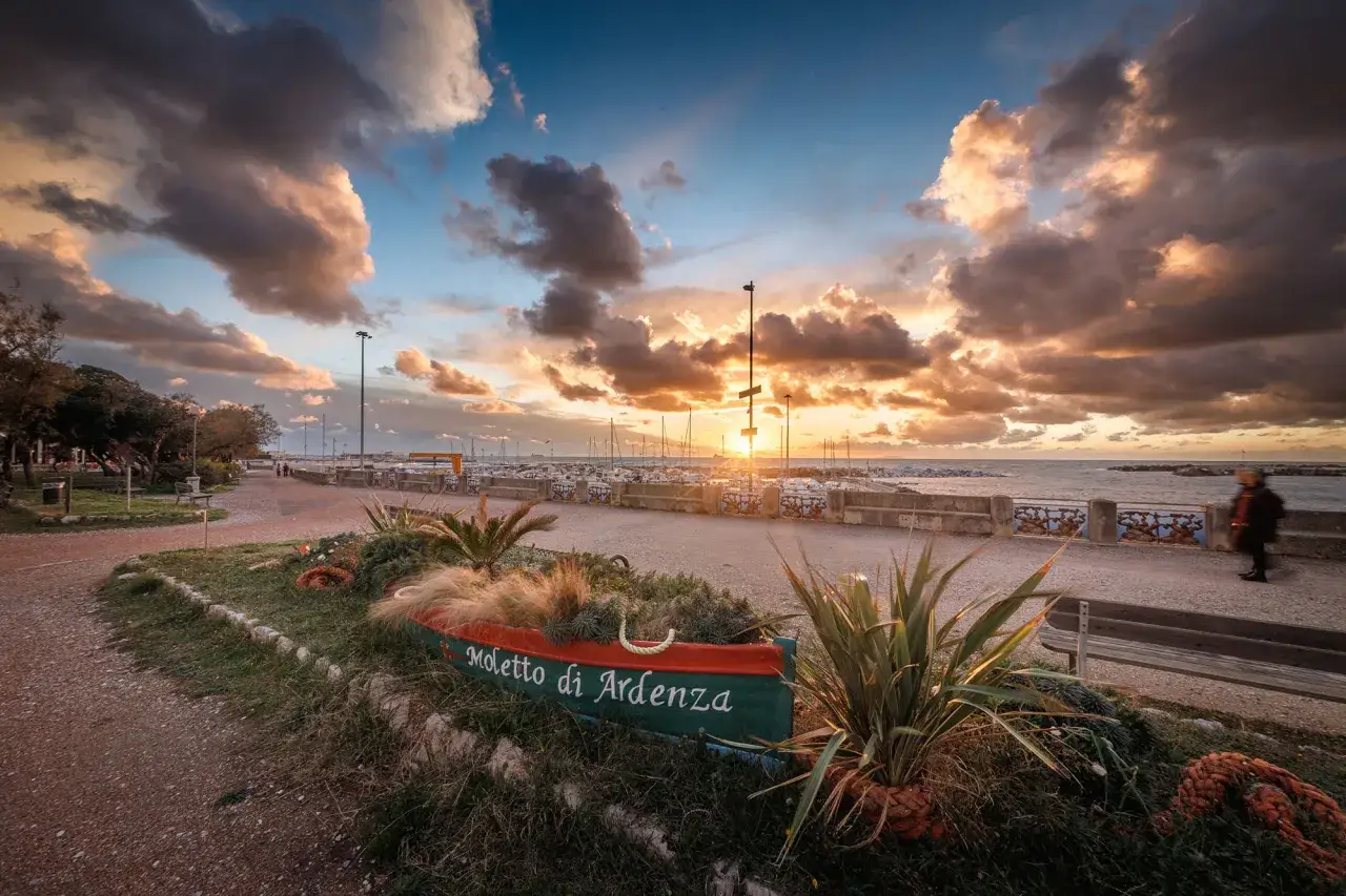 Tramonto dorato sul livorno mare, con nuvole spettacolari e un'antica barca trasformata in aiuola.