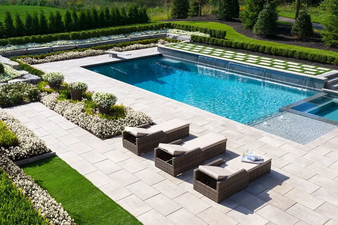 Ein luxuri&ouml;ser Garten mit Pool, Liegest&uuml;hlen und &uuml;ppiger Bepflanzung l&auml;dt zum Entspannen ein.
