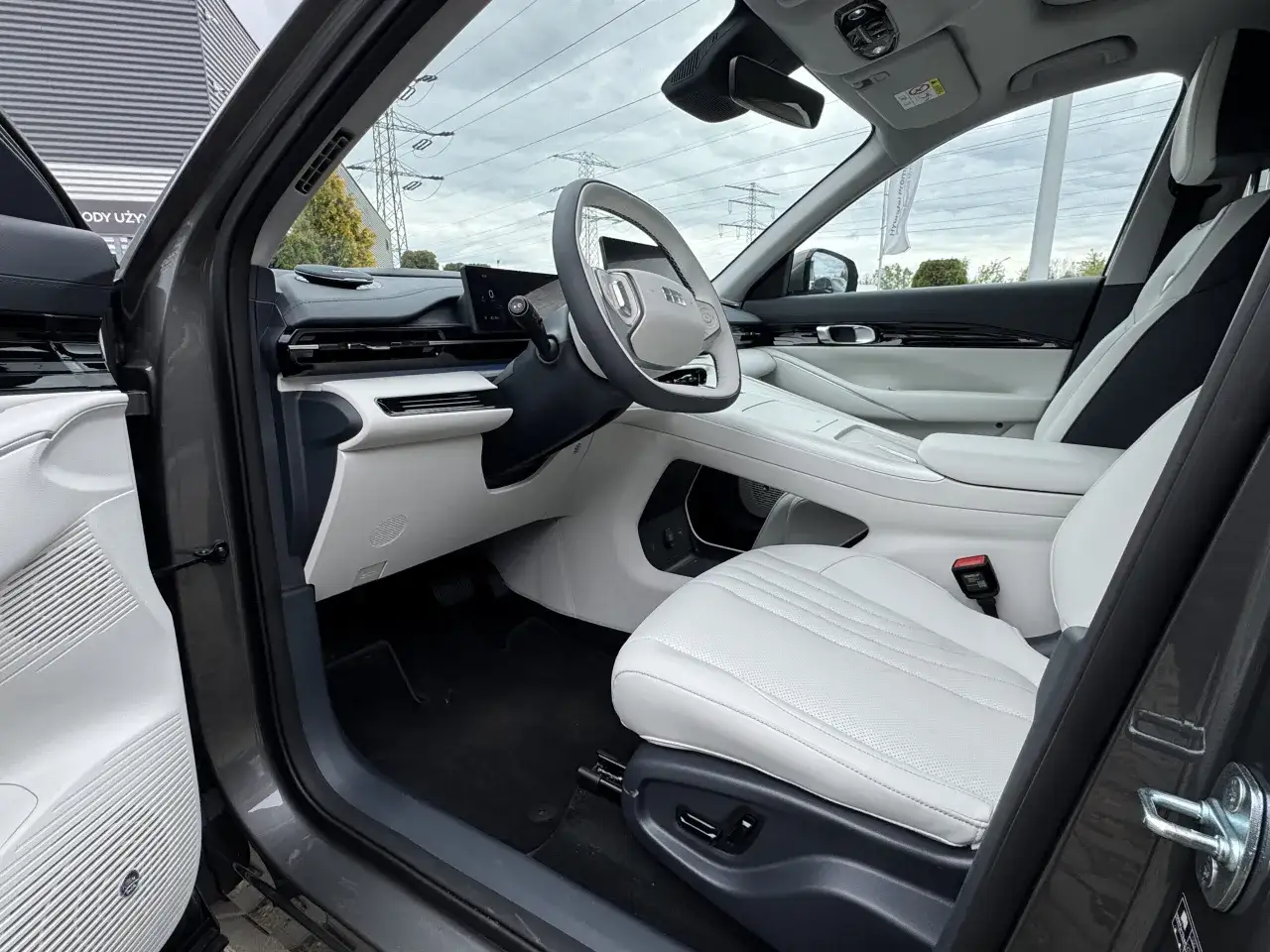 Wnętrze Geely EX5 z białymi skórzanymi fotelami i nowoczesnym panelem.
