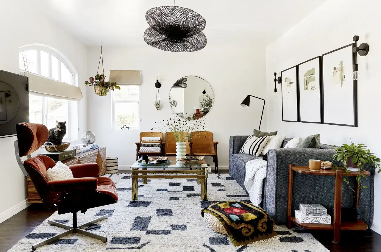 Gemütliches Wohnzimmer im Mid-Century-Stil mit orangefarbenem Sessel, grauem Sofa und einem auffälligen Teppich.