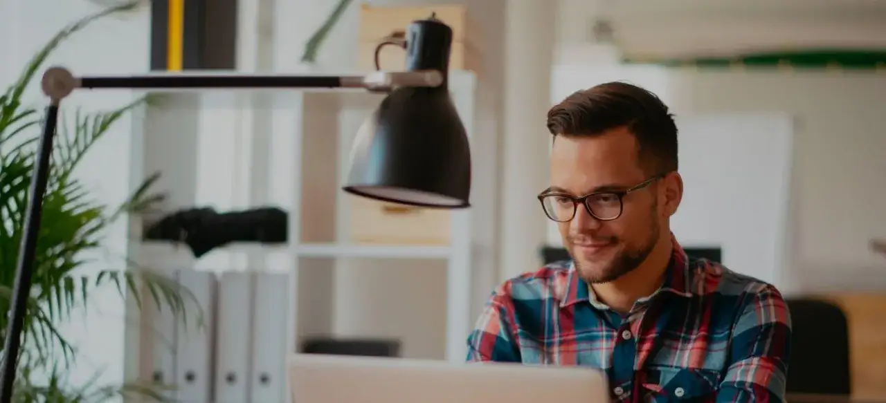 Junger Mann mit Brille am Laptop, der sich &uuml;ber sein Werkstudent Gehalt freut.