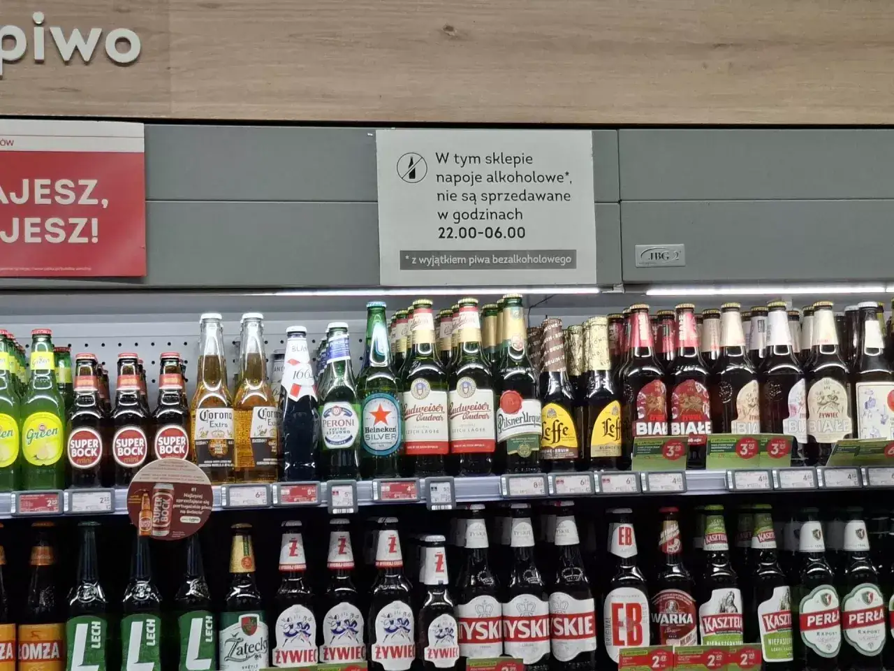 W tym sklepie zakaz sprzedaży alkoholu po 22:00. Wyjątkiem jest piwo bezalkoholowe. Rzędy piwa na półkach.