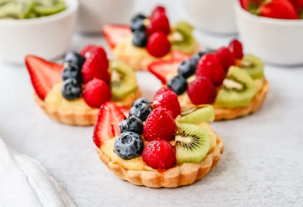 Pyszne tartaletki z kremem i owocami: truskawkami, malinami, borówkami i kiwi. Idealne na deser!
