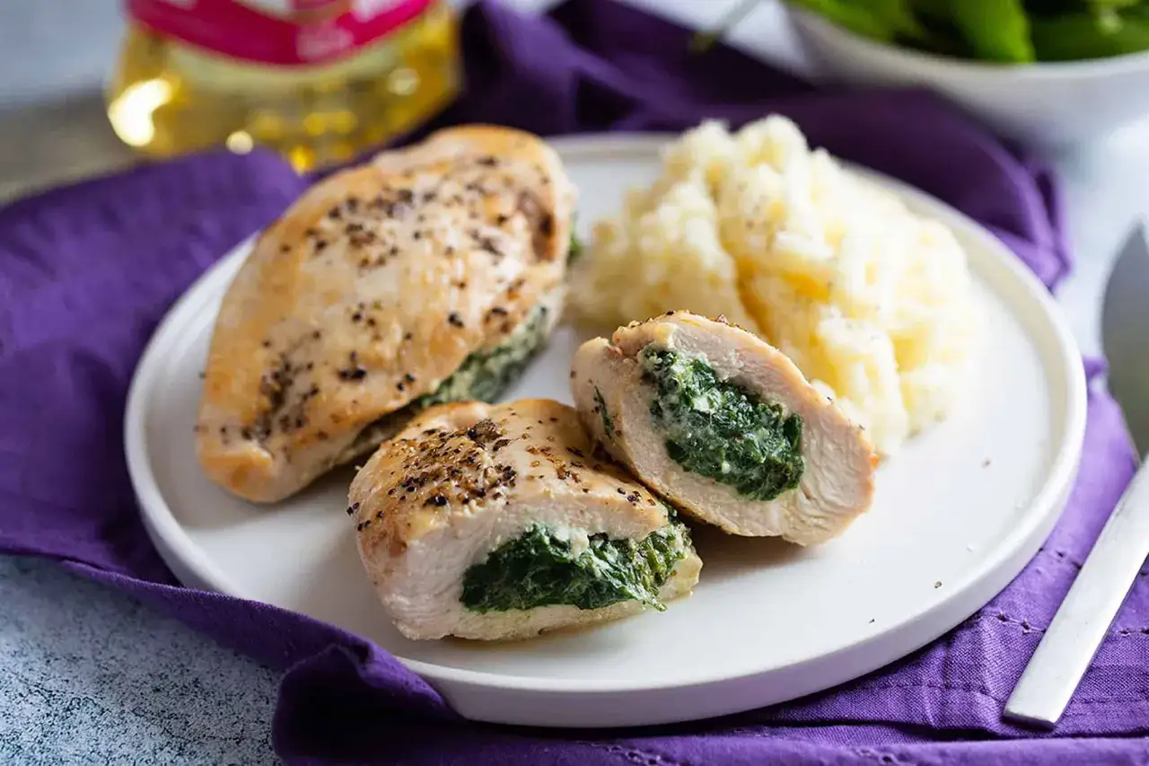 Pechugas de pollo rellenas de espinacas y queso, servidas con pur&eacute; de patatas.