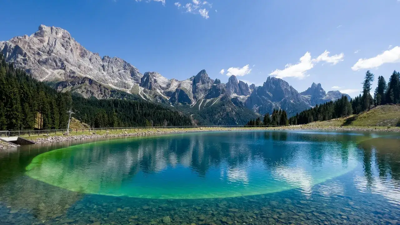 Lago alpino cristallino con montagne maestose sullo sfondo, un vero gioiello del Trentino Alto Adige.