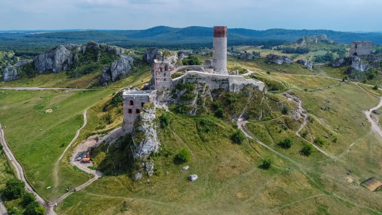 Ruiny zamku na skale w parku krajobrazowym Orlich Gniazd. W oddali las i wzgórza.